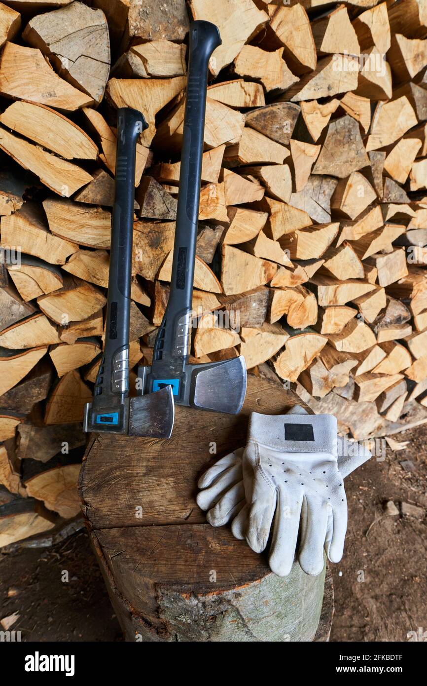 Hacha pesado sobre un muñón y guantes de protección de un leñador por una  pila de leña Fotografía de stock - Alamy