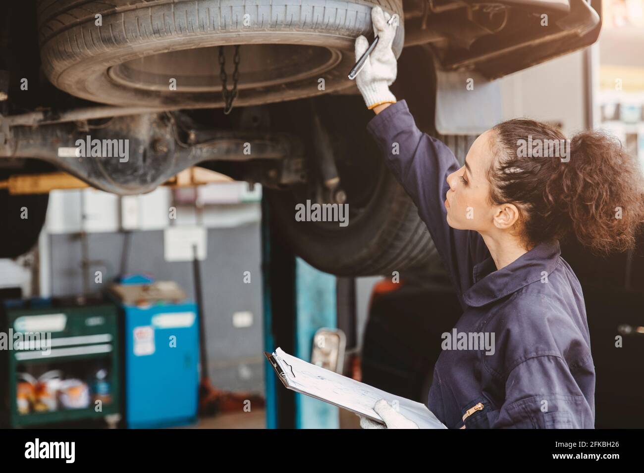 Mujer trabajador de garaje lista de comprobación de mantenimiento en el centro de servicio de automóviles, Mujer en mecánico de automóviles técnico de coches de trabajo de servicio de revisión y reparación cliente Foto de stock