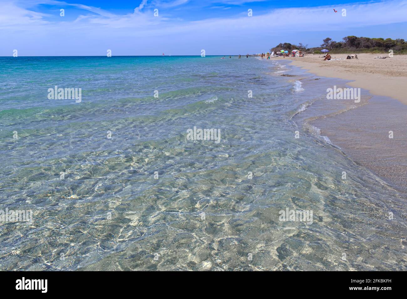 Relájese en la playa, Apulia (Italia). Camine por la playa y tome el sol a los turistas con una sombrilla solitaria entre Torre Mozza y Torre San Giovanni junto al mar. Foto de stock