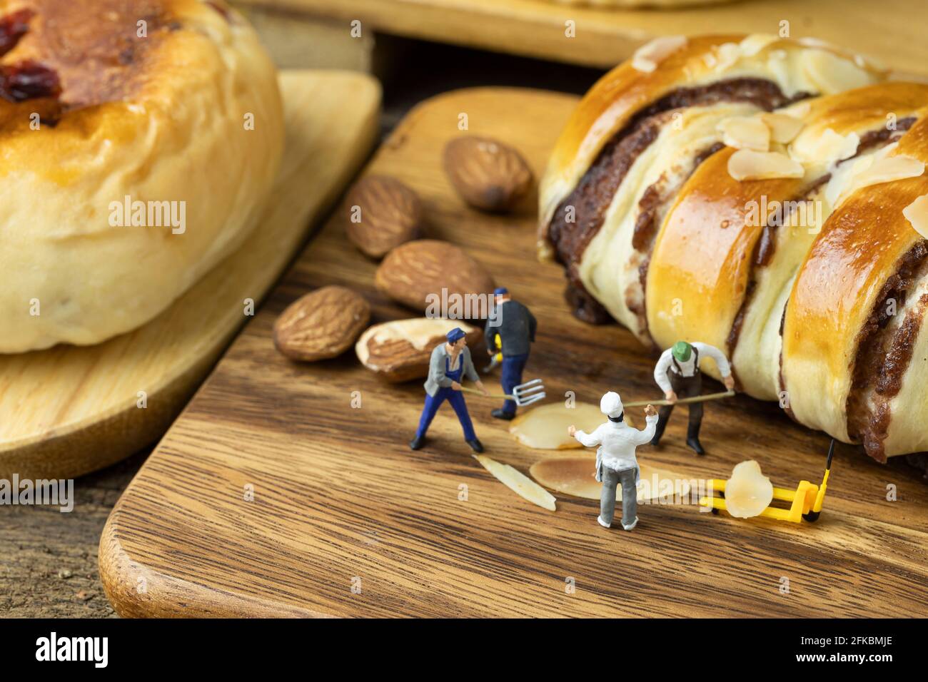 Mini Chef está instando a los trabajadores en miniatura a hacer pan en bandeja de madera Foto de stock