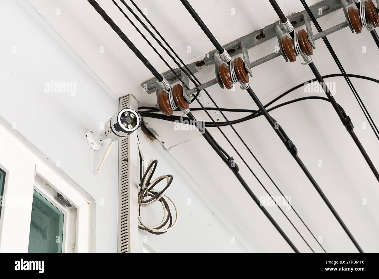 CCTV montado en la pared delantera de la casa. Y el cable principal para la fuente de alimentación. Foto de stock