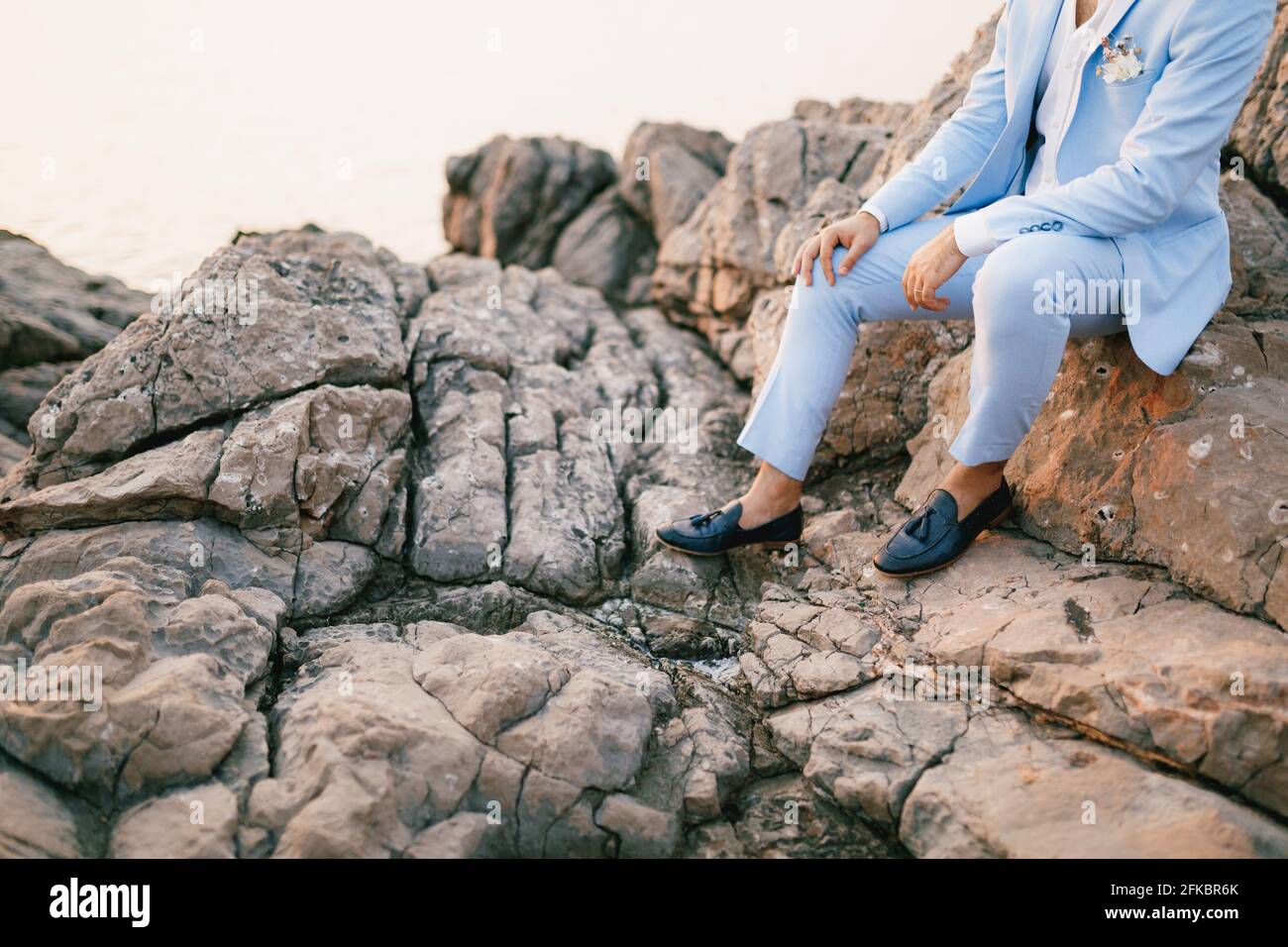 Un hombre en un traje azul con un boutonniere y. mocasines se en las rocas Fotografía de stock