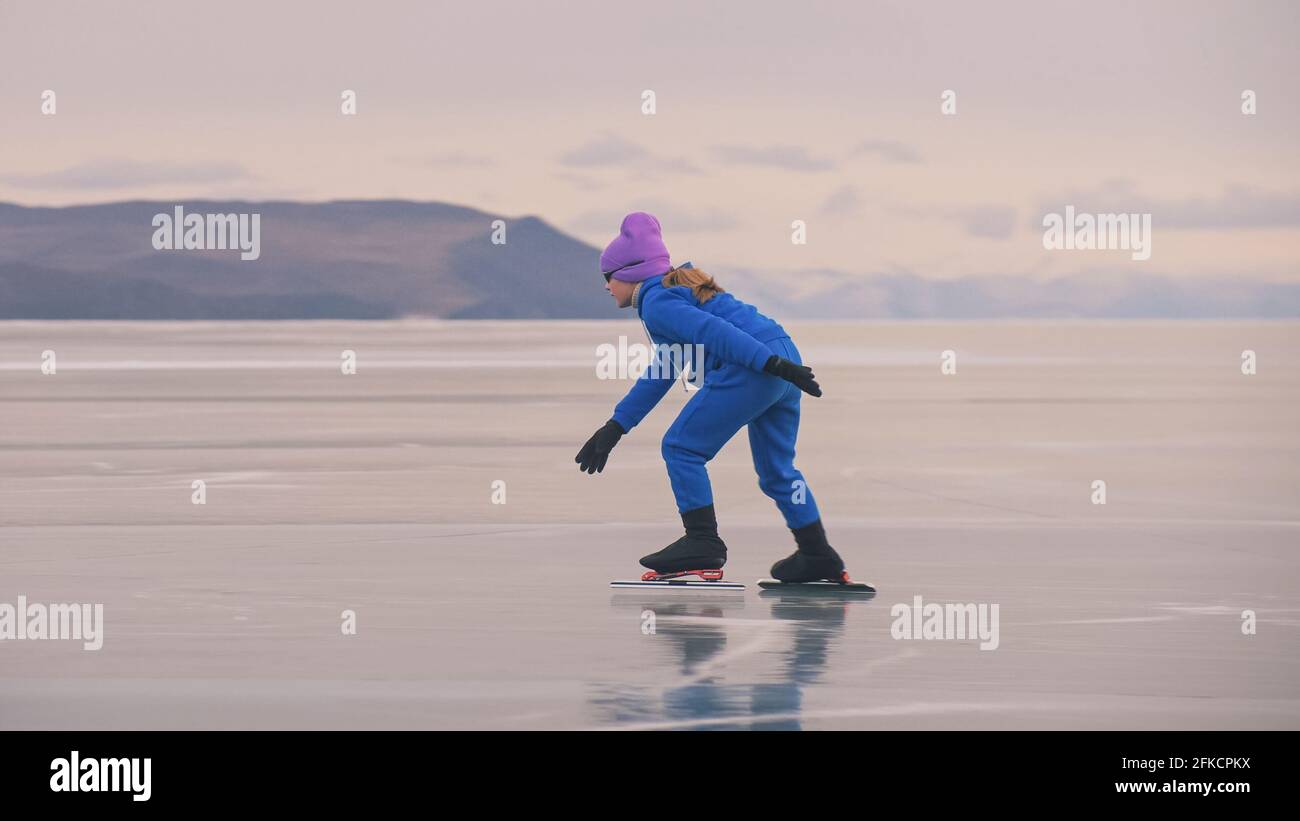La niña se entrena en patinaje sobre hielo. El niño patina en invierno con  traje azul de ropa deportiva, gafas deportivas. Deportes de patinaje de  velocidad para niños Fotografía de stock -