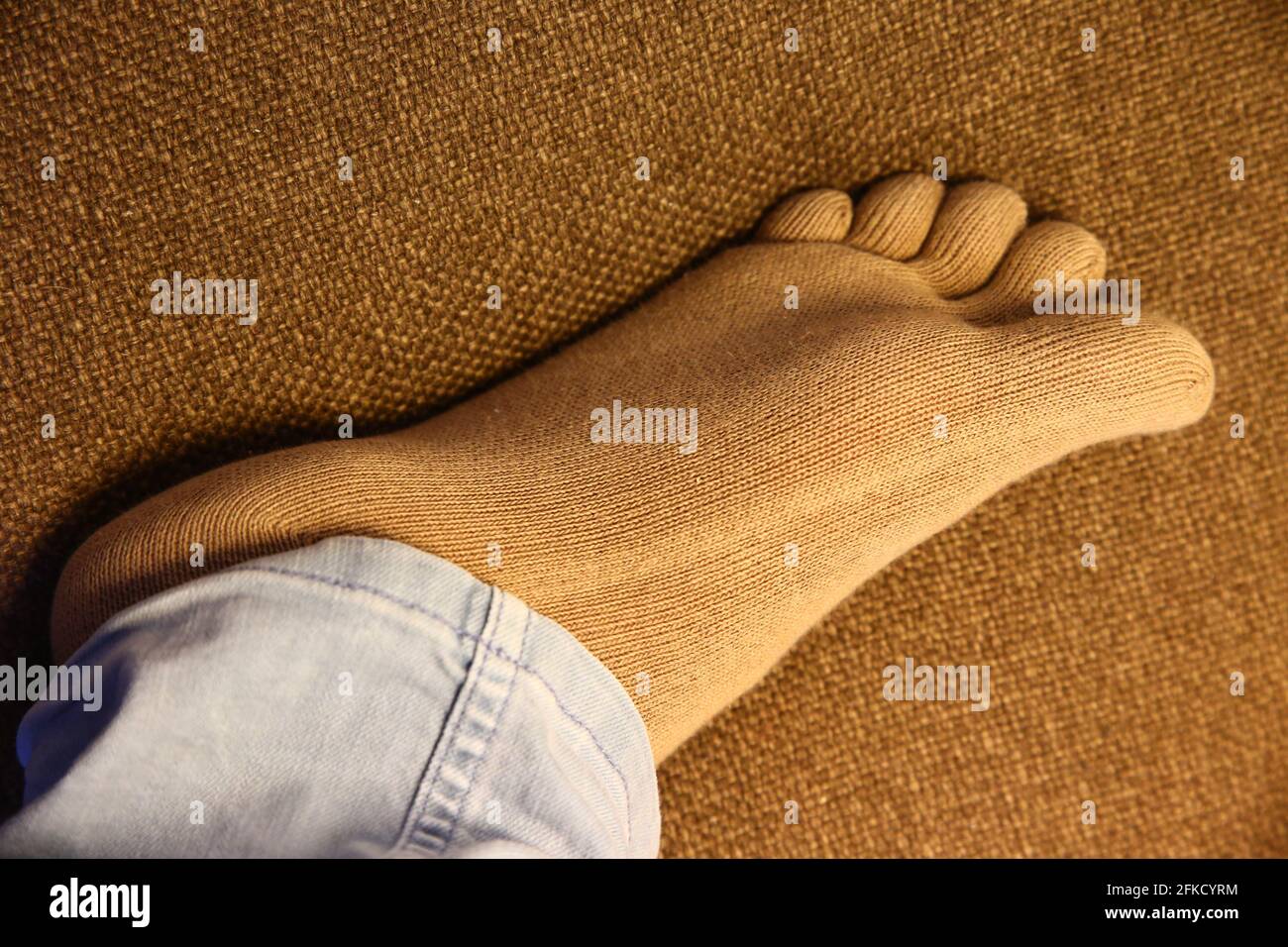 Calcetines sanos con el dedo que llevan el pie sobre el sofá en la imagen de cerca que muestra la suela. Foto de stock