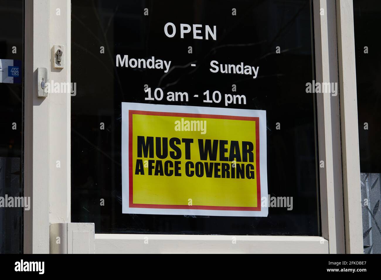 Londres, Reino Unido - 16 de abril de 2021: Un aviso contundente pide a los clientes que lleven una cubierta facial en un negocio minorista durante la pandemia del coronavirus. Foto de stock
