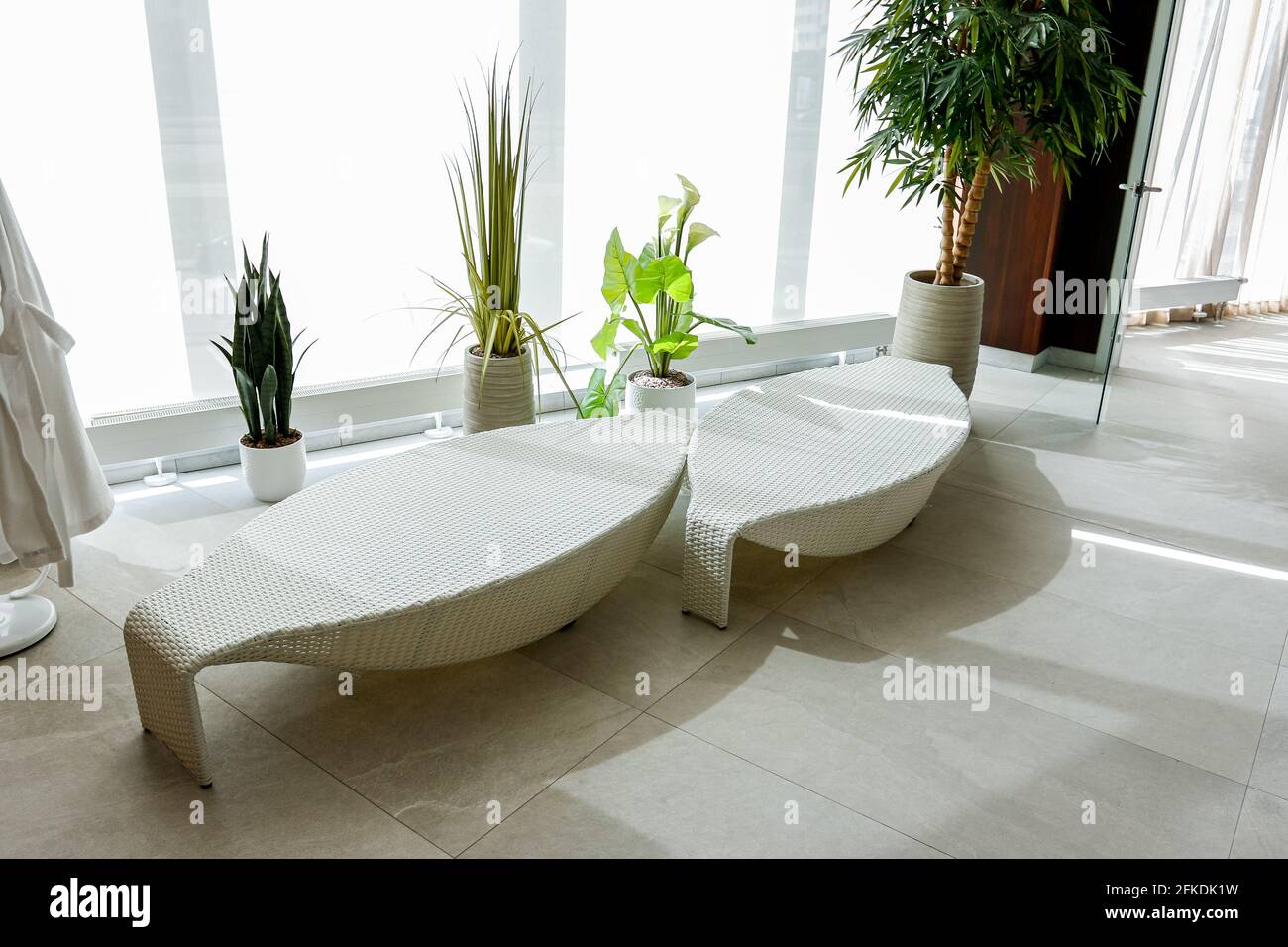 Hay tumbonas blancas de diseño junto a la piscina en un spa de lujo. Foto de stock