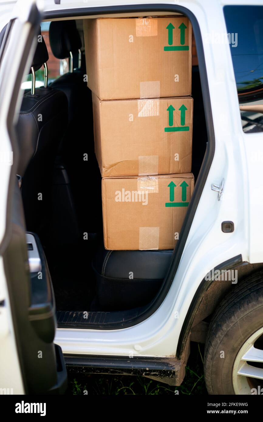 Tres cajas de cartón de color verde cantan de esta manera en el asiento trasero de un coche blanco. Foto de stock