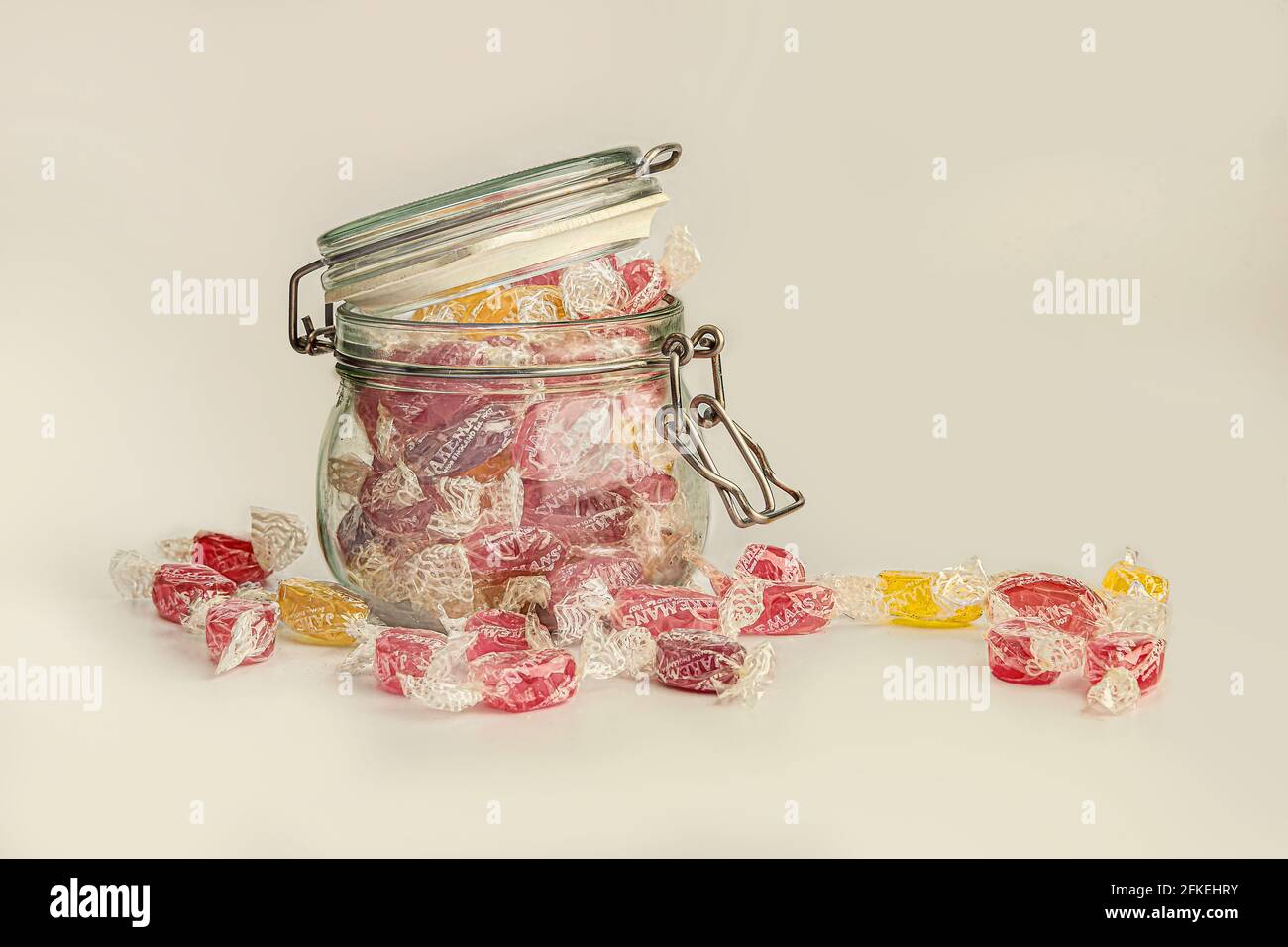 El tarro de Kilner llenó a desbordar con los dulces de la tos en un Fondo blanco Foto de stock