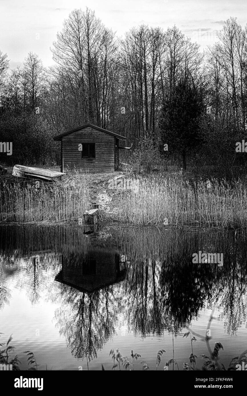 casa de madera en el bosque cerca del lago. lugar tranquilo. Una antigua casa de madera para descansar está en el agua. Agua, estanque, lago, cerca de la orilla Foto de stock