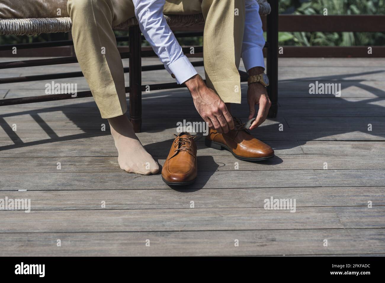El macho está lazando zapatos marrones elegantes que se sientan en el banco  exterior Fotografía de stock - Alamy