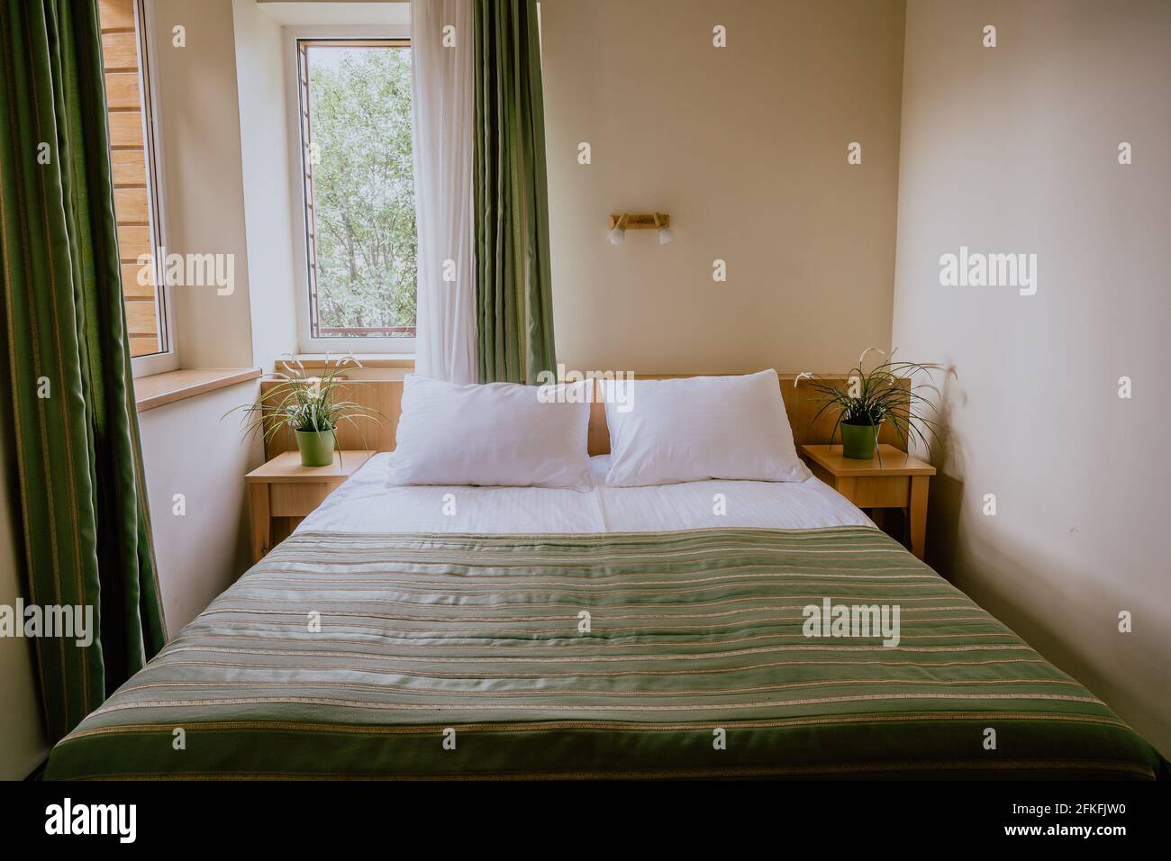 Habitación de hotel pequeña con una cama doble y dos camas de noche mesas decoradas con Fotografía de stock - Alamy