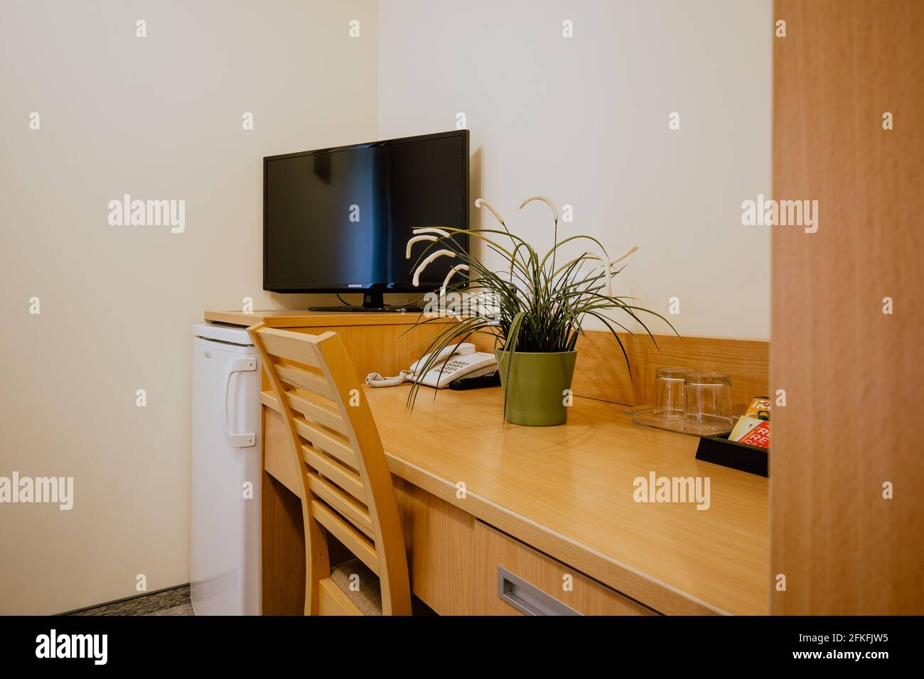 Un escritorio de trabajo de madera decorado con plantas en un hotel  habitación junto a una nevera y tv Fotografía de stock - Alamy