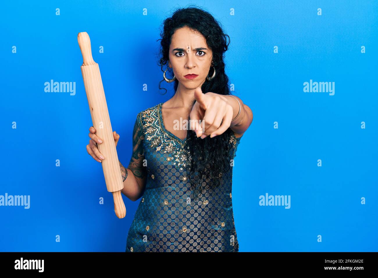 Mujer joven con bindi y tradicional vestido kurta sosteniendo un rodillo de  amasado apuntando con el dedo a la cámara y a ti, gesto seguro s Fotografía  de stock - Alamy
