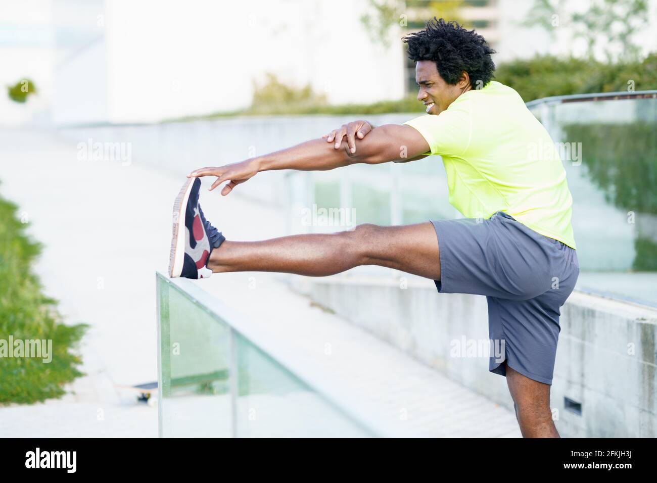Hombre negro con pelo afro que se estira después de correr al aire libre. Foto de stock