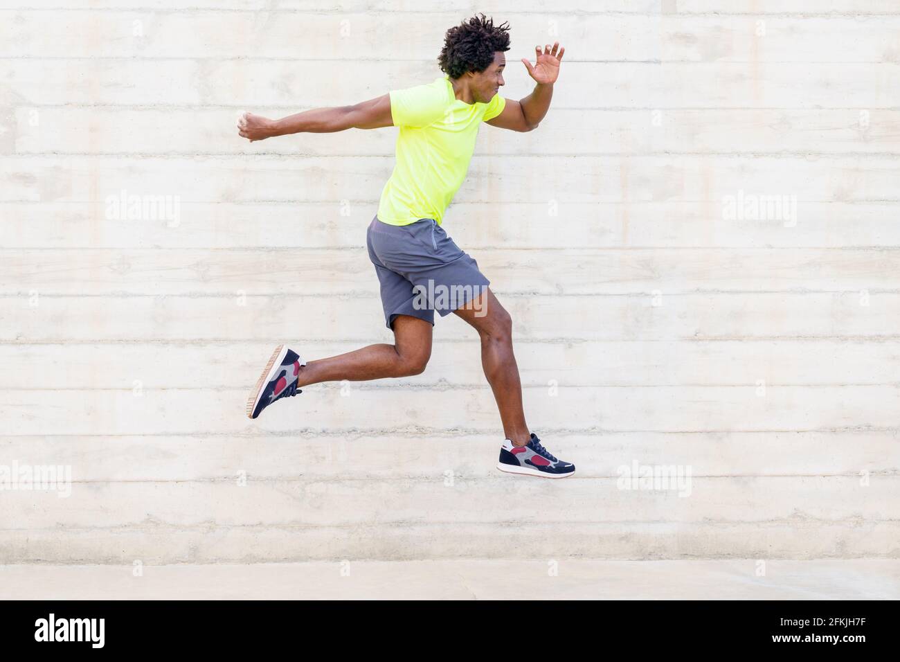 Hombre negro entrenamiento correr saltos para fortalecer sus piernas. Foto de stock