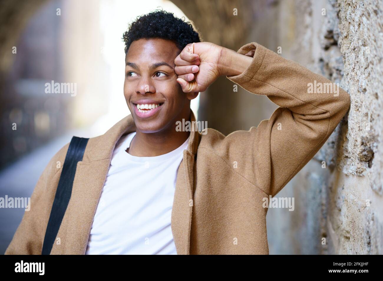 Feliz joven negro sonriendo en el fondo urbano. Foto de stock