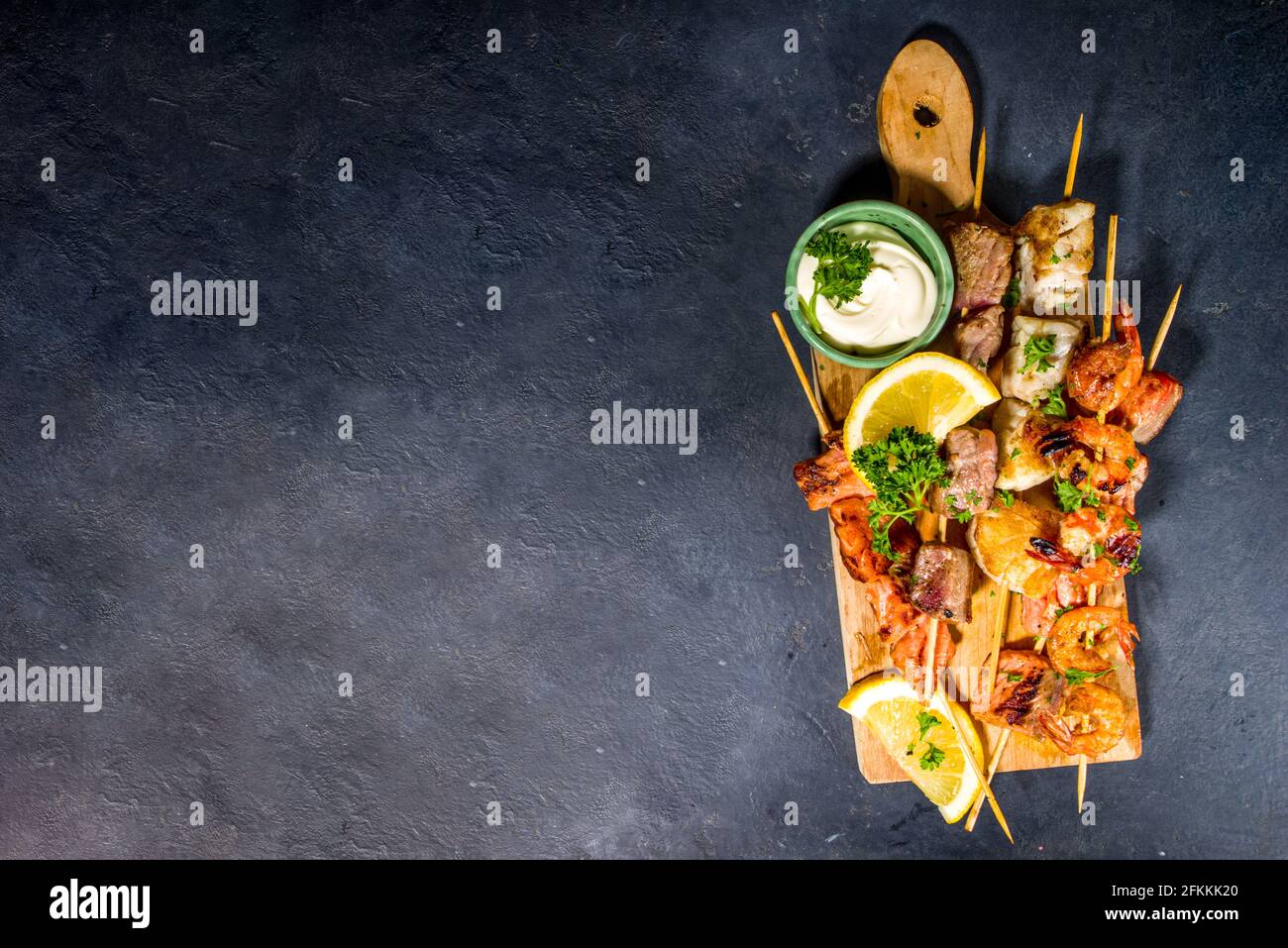 Surtido de varios alimentos barbacoa mediterránea parrilla - pescado, camarones, cangrejo, mejillones, kebabs con salsas, fondo de hormigón negro, sobre el espacio de copia Foto de stock