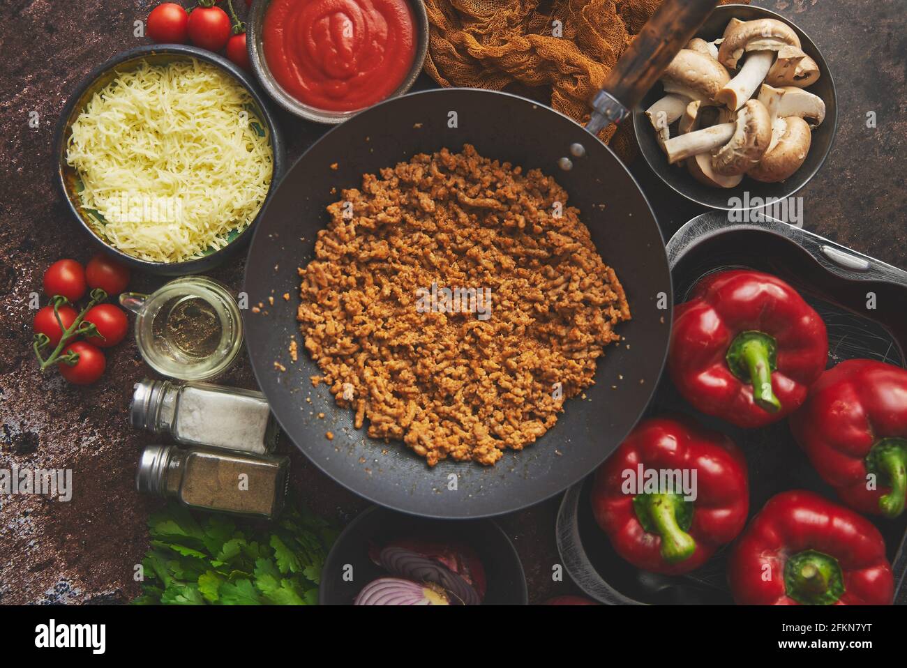 Ingredientes en una mesa preparada para el relleno de pimientos. Pimientos rojos, carne picada, queso Foto de stock