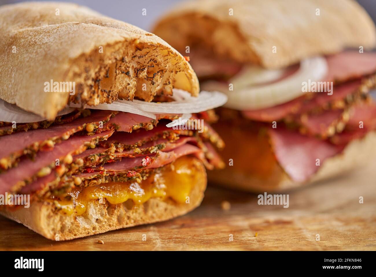 Sándwich de pástrami de corte fino con deliciosa comida en pan baguette con queso chedder, cebolla Foto de stock