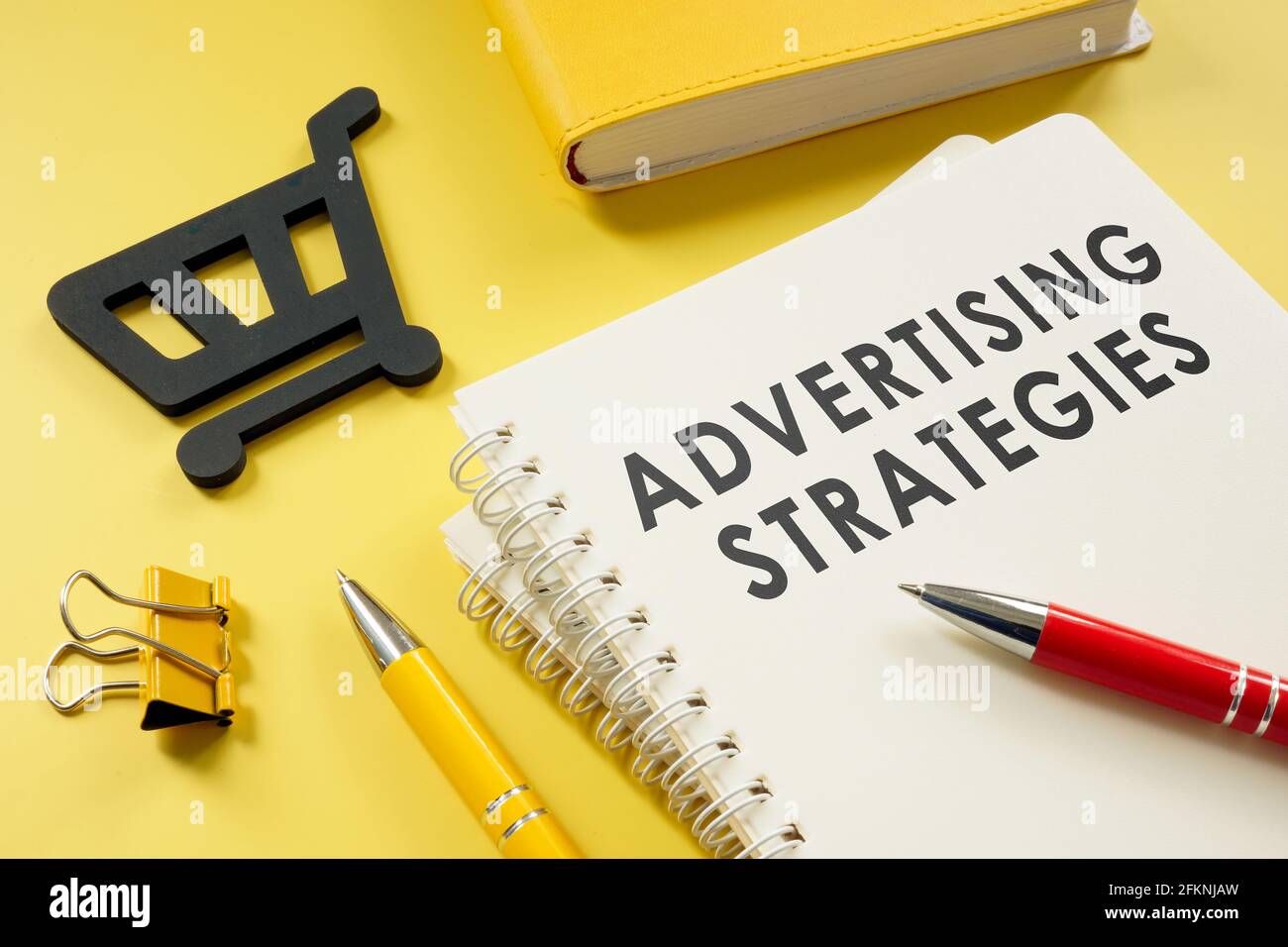 Estrategias de publicidad plan en el escritorio y carrito de compras. Foto de stock