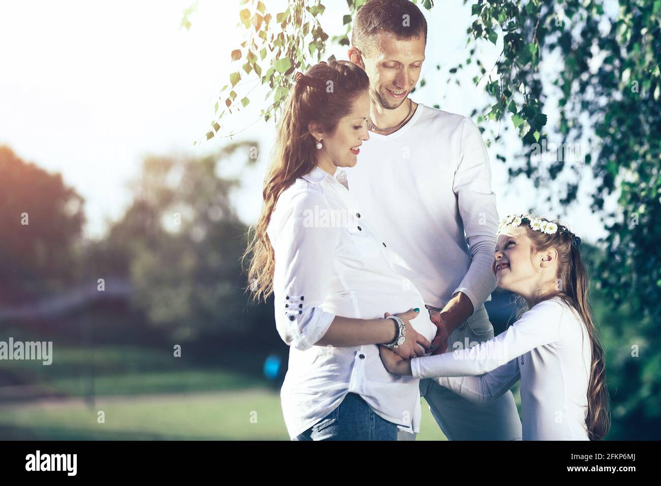 Feliz el padre y la niña abrazando a su madre embarazada en una wa Foto de stock