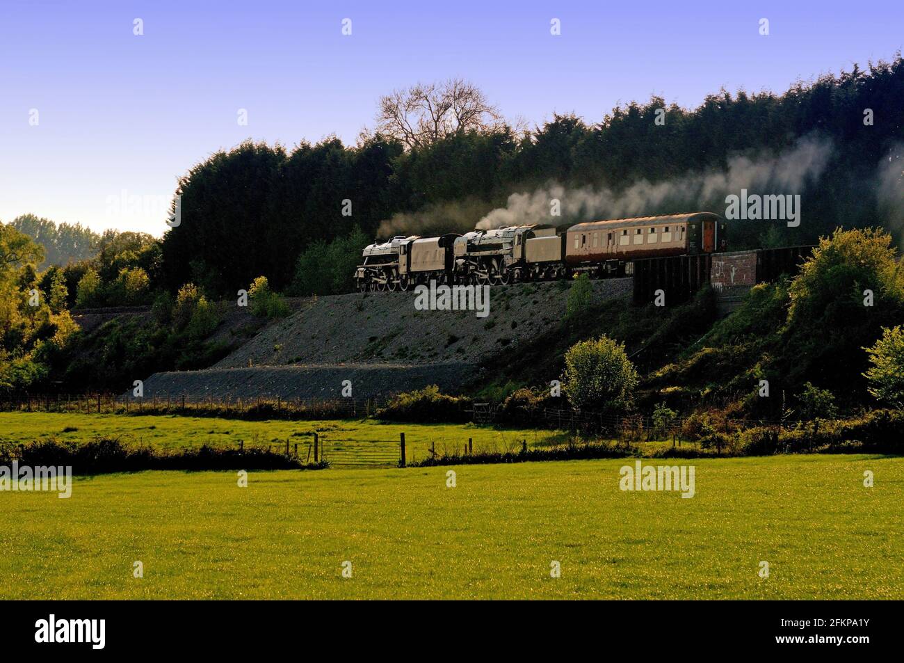 Por la noche, el sol Negro Five No 45305 y el BR Standard No 70013 Oliver Cromwell se dirigen al oeste con un autobús de apoyo para recoger el ferrocarril Gran Bretaña 4. Foto de stock