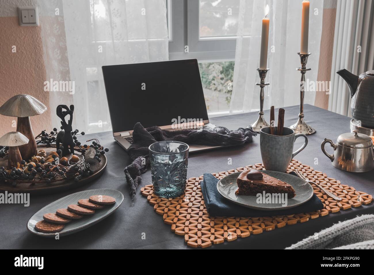 Mesa con ordenador portátil, pastel, galletas y decoración otoñal en una  acogedora sala preparada para café virtual con la familia o amigos, útil  durante todo el mundo CO Fotografía de stock -