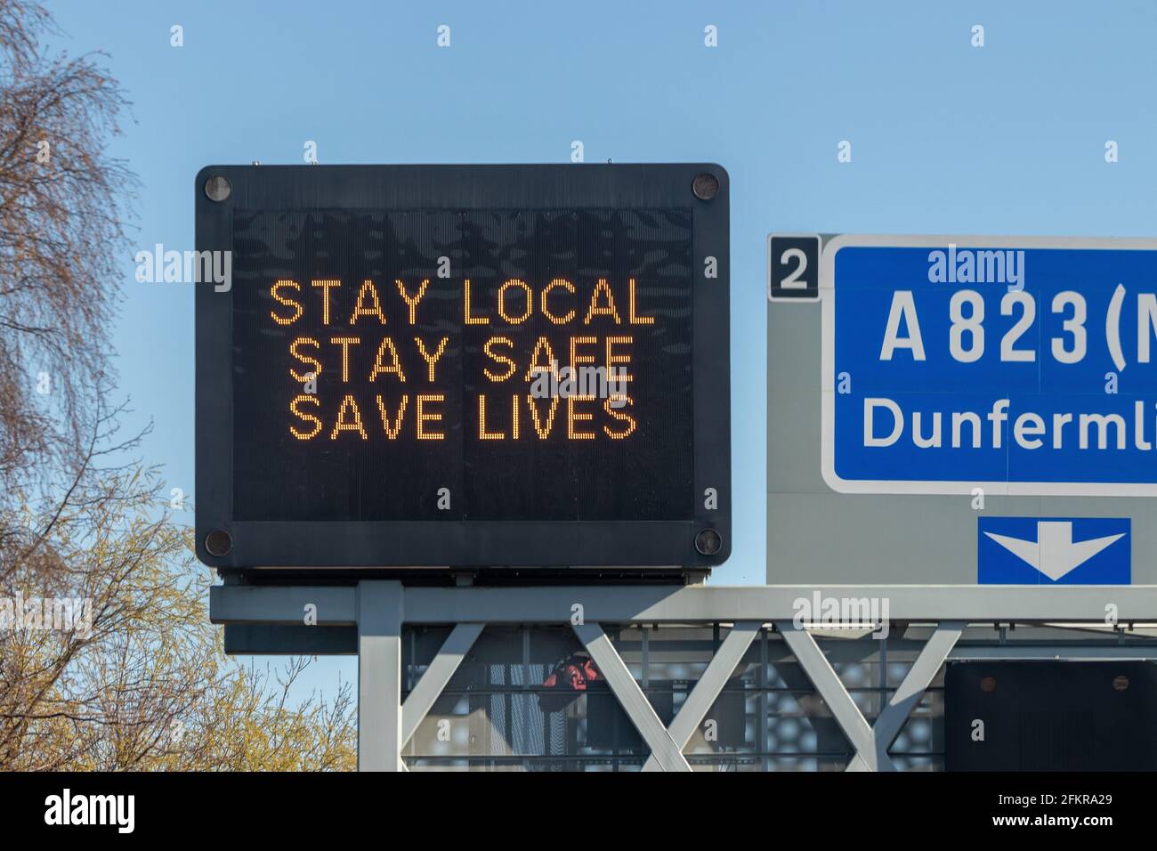 Una señal de autopista en Escocia que dice Stay Local, Stay Safe, Save Lives Foto de stock