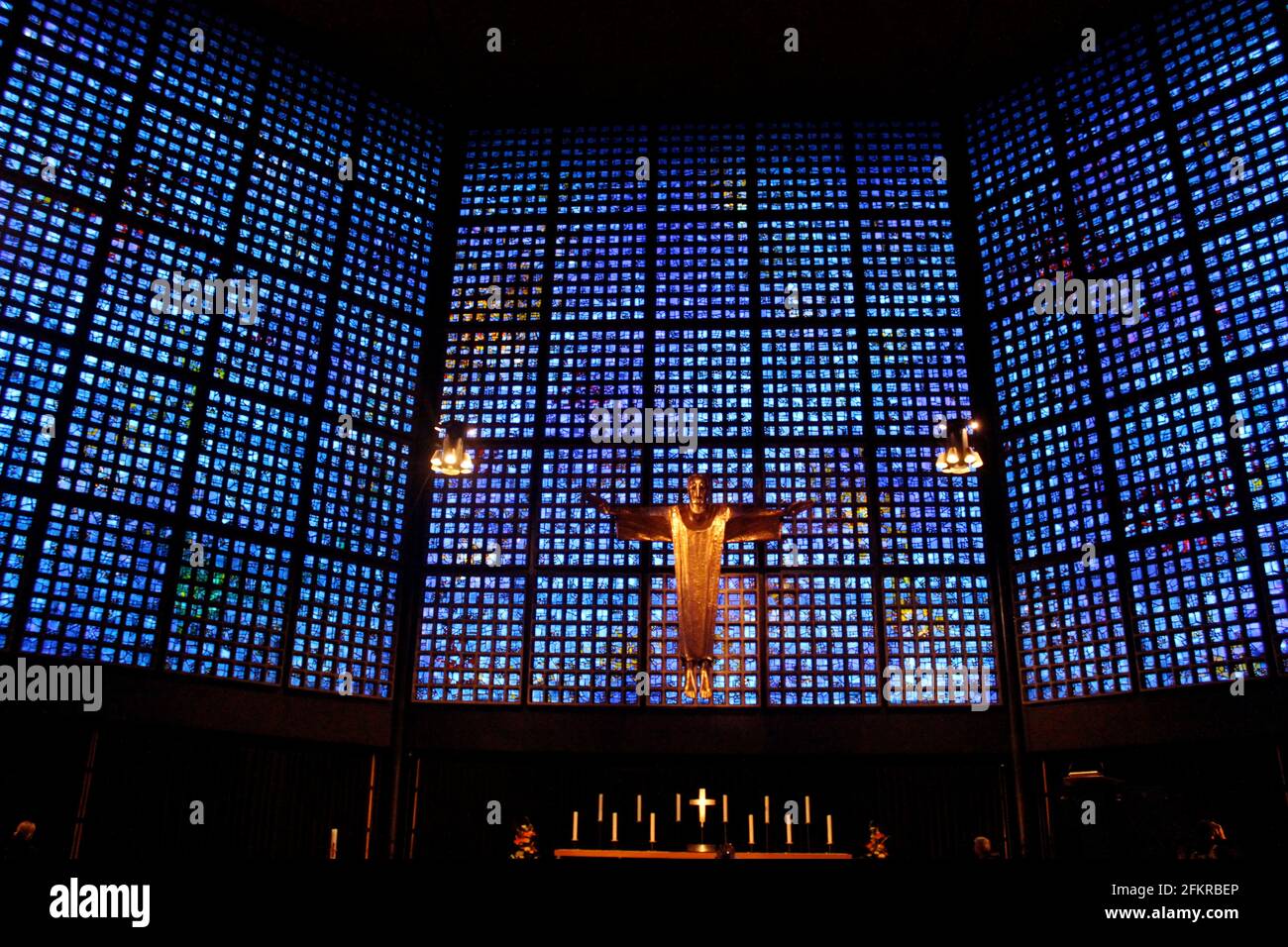 Interior de la Iglesia Memorial Kaiser Wilhelm en Belin, Alemania, con vidrio azul y púrpura y estatua de Jesús sobre el altar Foto de stock