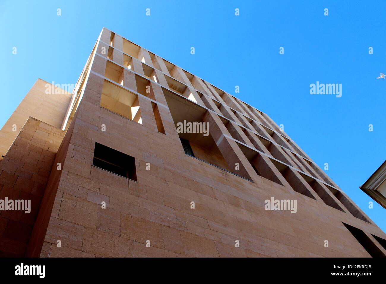 Edificio moderno de piedra arenisca rectalinear desde abajo con un cielo azul claro en el fondo. Ayuntamiento de Murcia, Murcia, España por Rafael Moneo Foto de stock