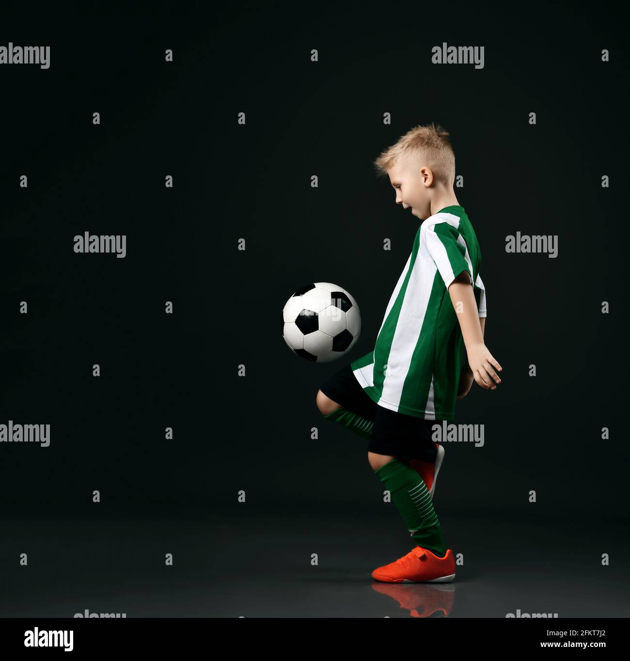 Jugador de fútbol joven, chico chico en rojo blanco rayas camisa uniforme,  pantalones cortos, medias está golpeando la pelota con la rodilla  Fotografía de stock - Alamy