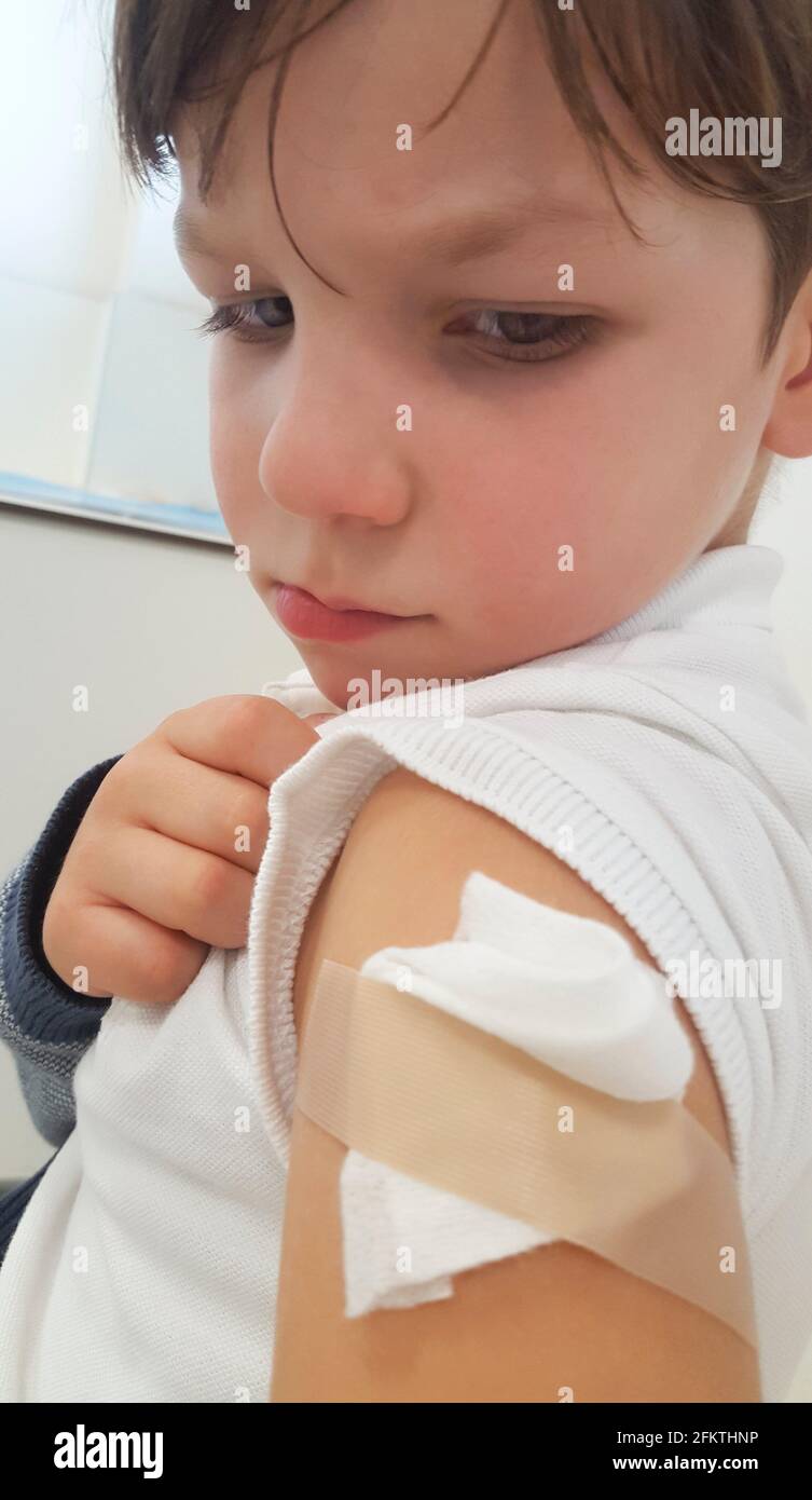 Triste y con dolor niño niño muestra su brazo después de la vacunación. Enfoque selectivo. Foto de stock