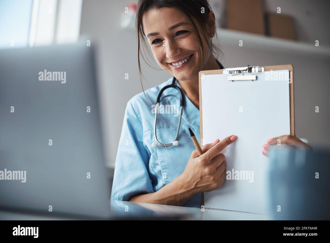 Buena mujer médico dando consulta en línea en la clínica Foto de stock