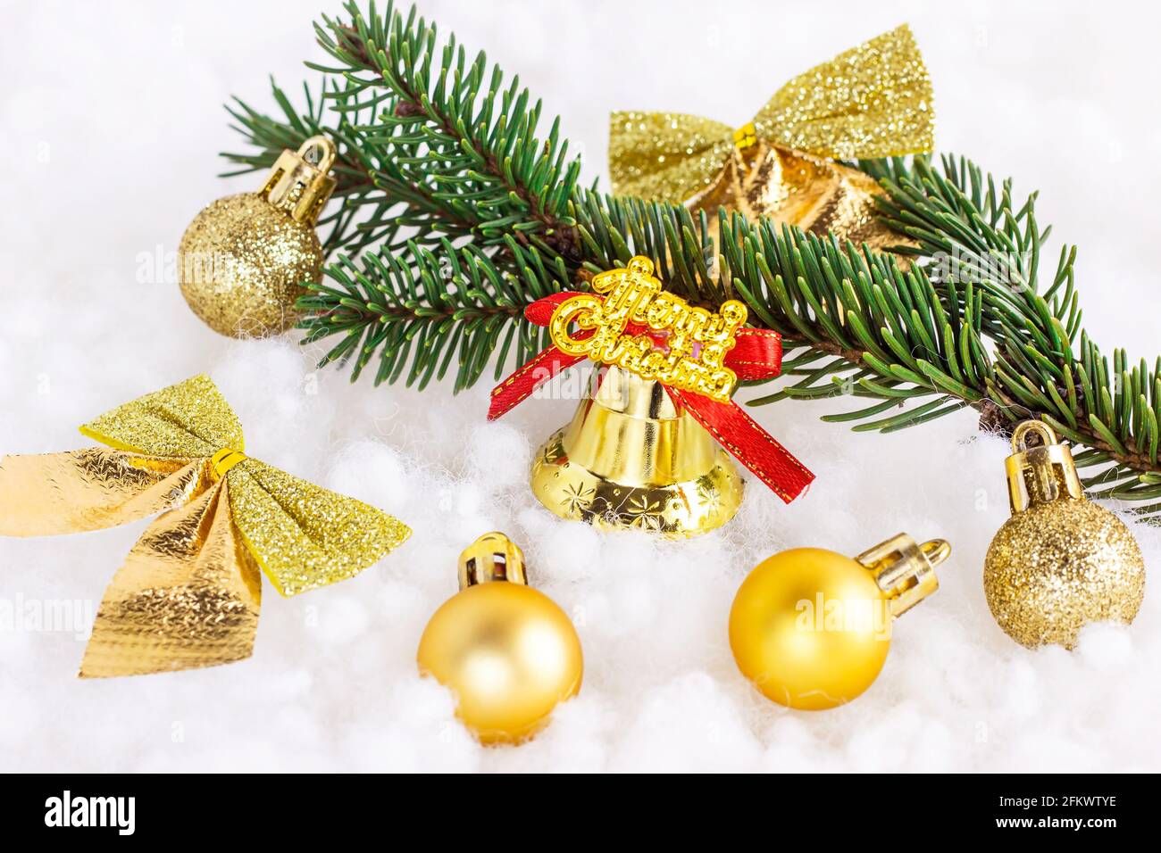 Decoraciones navideñas brillantes doradas y amarillas (cintas, bolas,  adornos, campana) con rama de abeto sobre fondo blanco de nieve artificial.  Navidad Fotografía de stock - Alamy