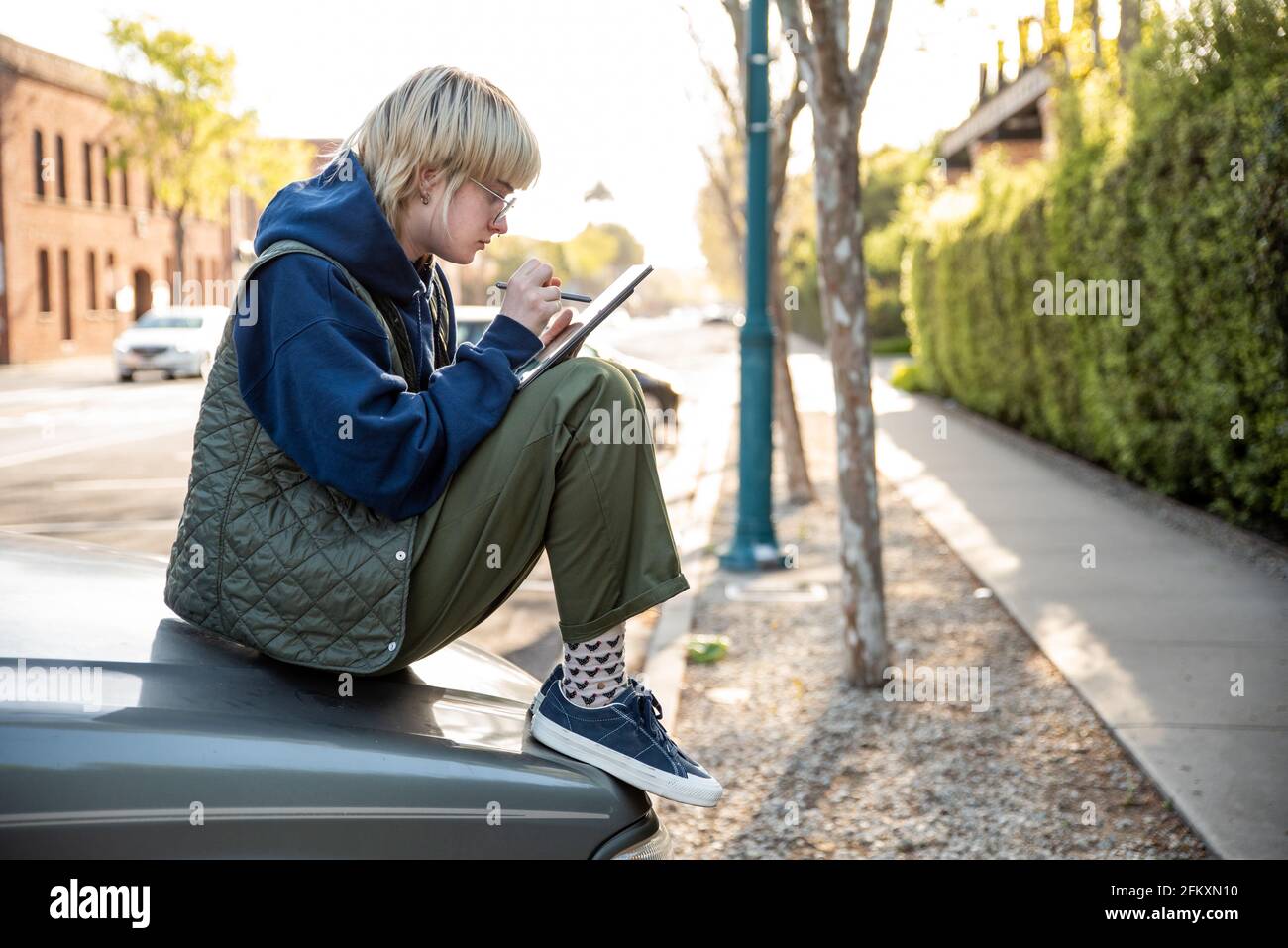 Adulto joven sentado en la capucha del camión con el lápiz óptico y.  tableta para trabajar Fotografía de stock - Alamy