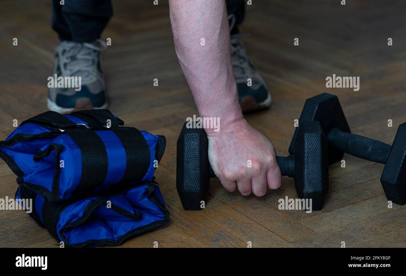 Aplicado chupar circuito Equipo para ejercitar los músculos de los brazos y piernas. Pesas y sacos  de arena en el piso de madera. El hombre toma una mancuerna y la recoge  Fotografía de stock -