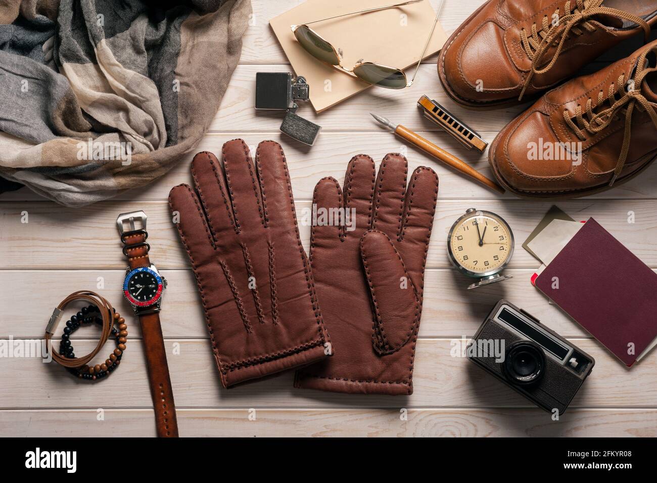 Un par de guantes de cuero marrón para hombre y otros accesorios