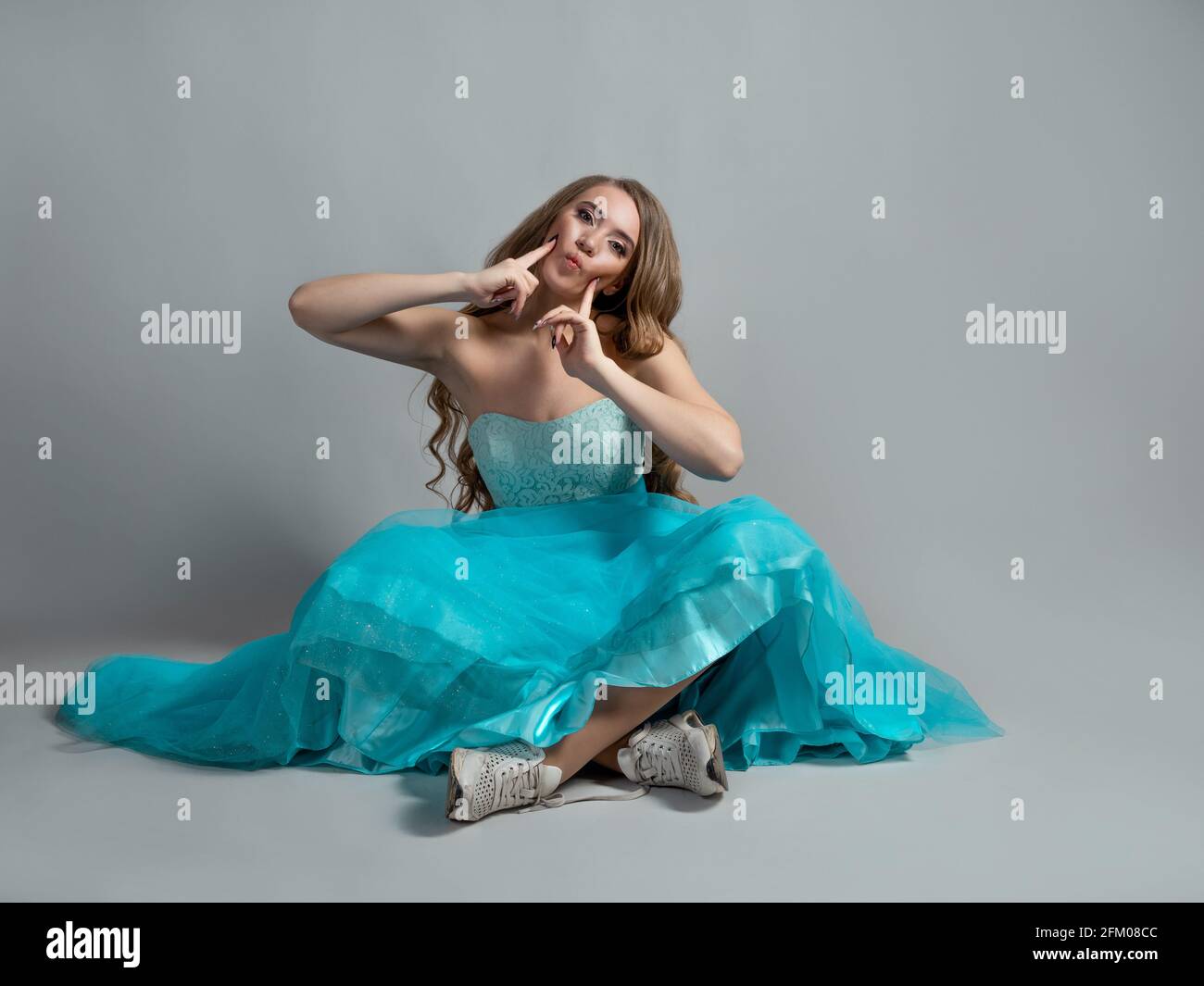 Hermosa y atrevida princesa con un vestido y unas sneakers de color azul  intenso de Cenicienta, de estilo moderno. Mujer joven sentada en el suelo  Fotografía de stock - Alamy