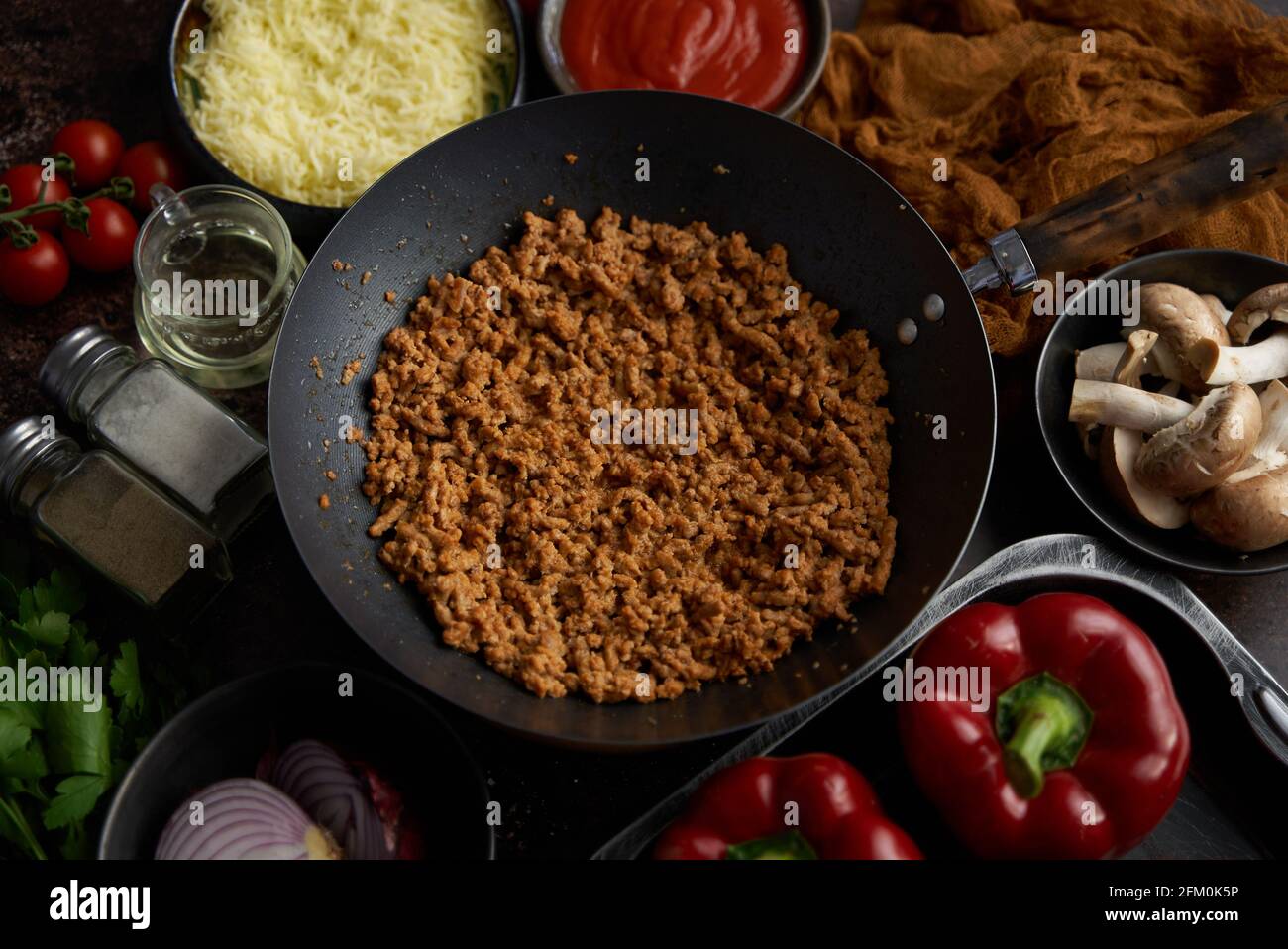 Ingredientes en una mesa preparada para el relleno de pimientos. Pimientos rojos, carne picada, queso Foto de stock