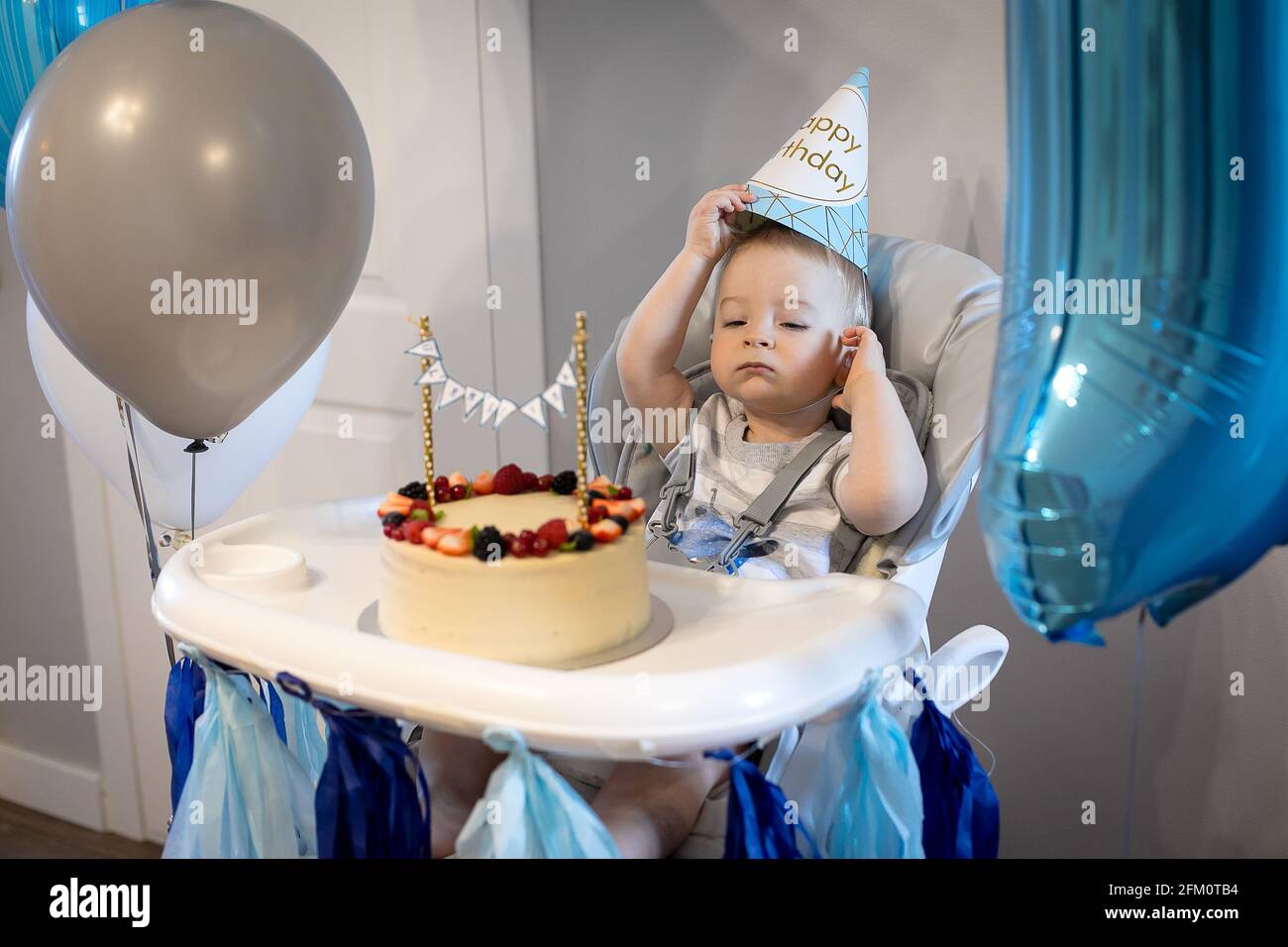 Niño caucásico celebrando su primer cumpleaños en casa. Pastel de cumpleaños.  Decoración azul, globo Fotografía de stock - Alamy