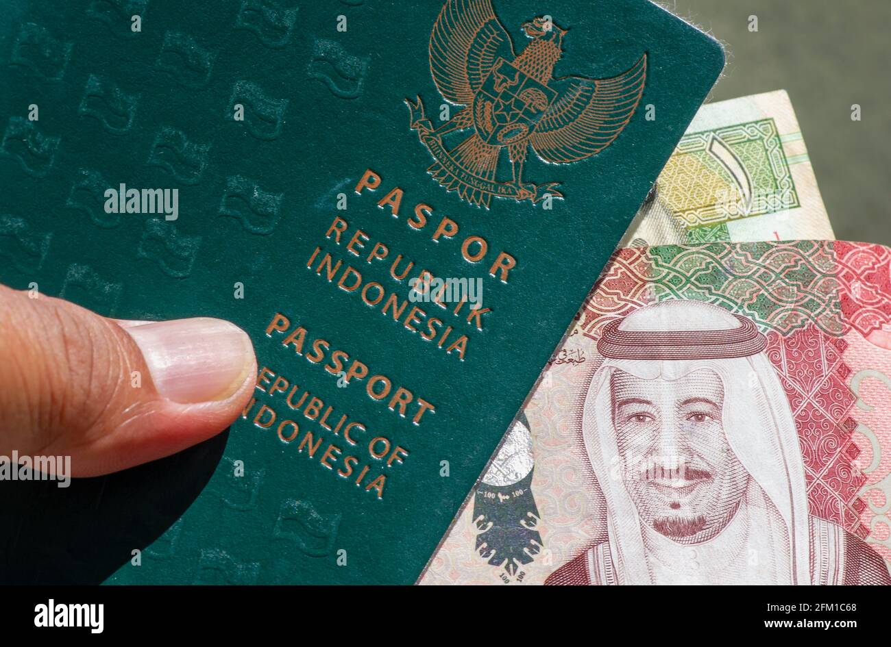 Primer plano del pasaporte verde indonesio y de la Riyal Saudita, la moneda de Arabia Saudita, para la preparación de peregrinos procedentes de Indonesia Foto de stock