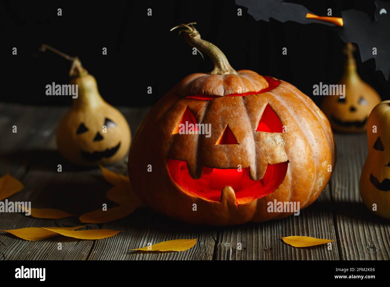 Diseño de Halloween con calabazas. Horrible símbolo de Halloween - Jack-o- linterna. Cabeza de calabaza de miedo con llama y unas pequeñas calabazas  pintadas. Glowin Fotografía de stock - Alamy