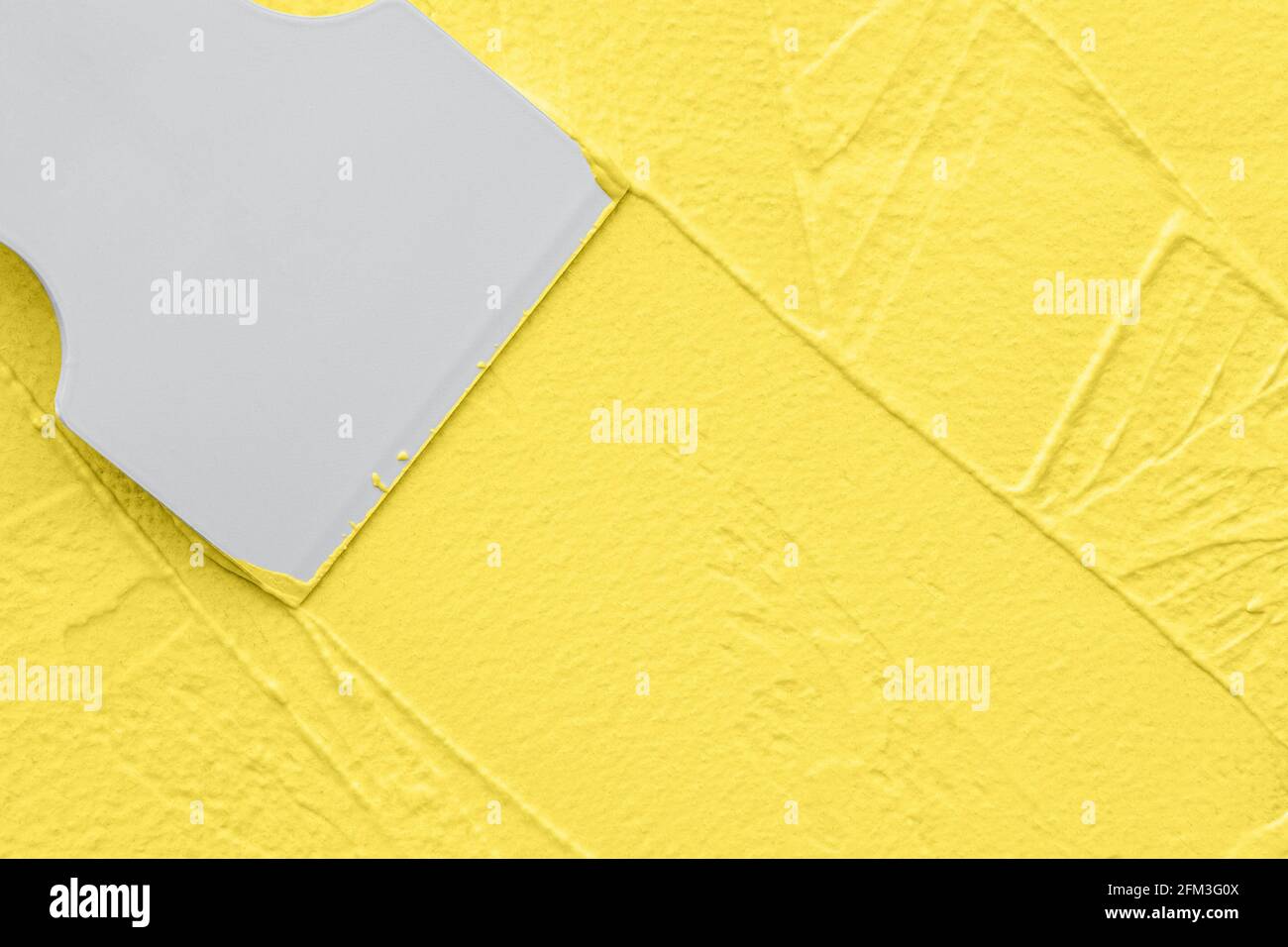 Aplicando masilla amarilla con espátula, trabajos de redecoración interior Foto de stock