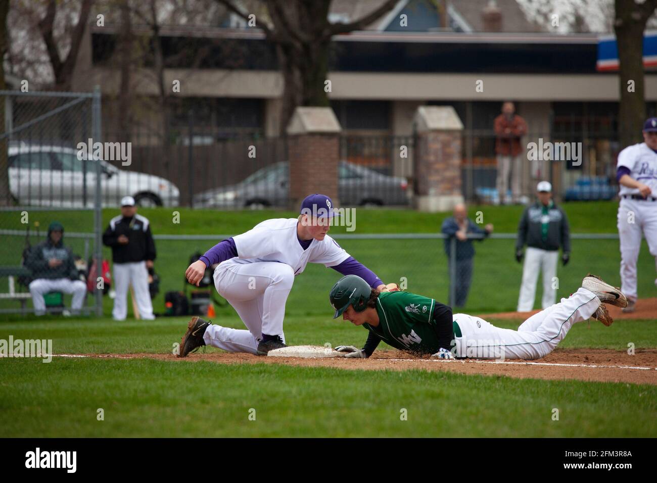 El jugador de béisbol deslizando la cabeza hacia la base y el jugador tratando de marcarlo en el Cretin Durham Hall Field. St Paul Minnesota MN EE.UU Foto de stock