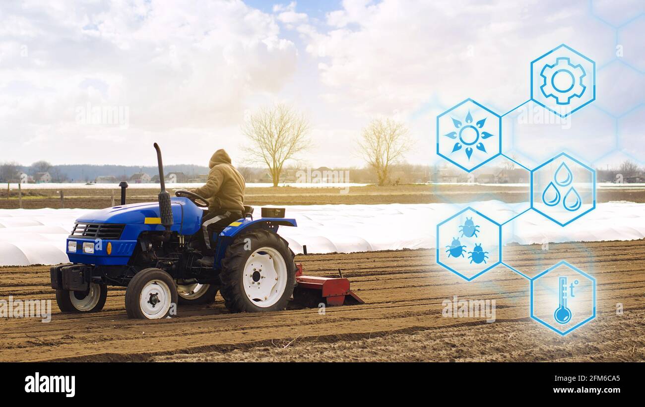 El agricultor en un tractor con fresadora afloja, muele y mezcla el suelo. Startups agrícolas, mejoras, digitalización de la industria agrícola. Inn Foto de stock