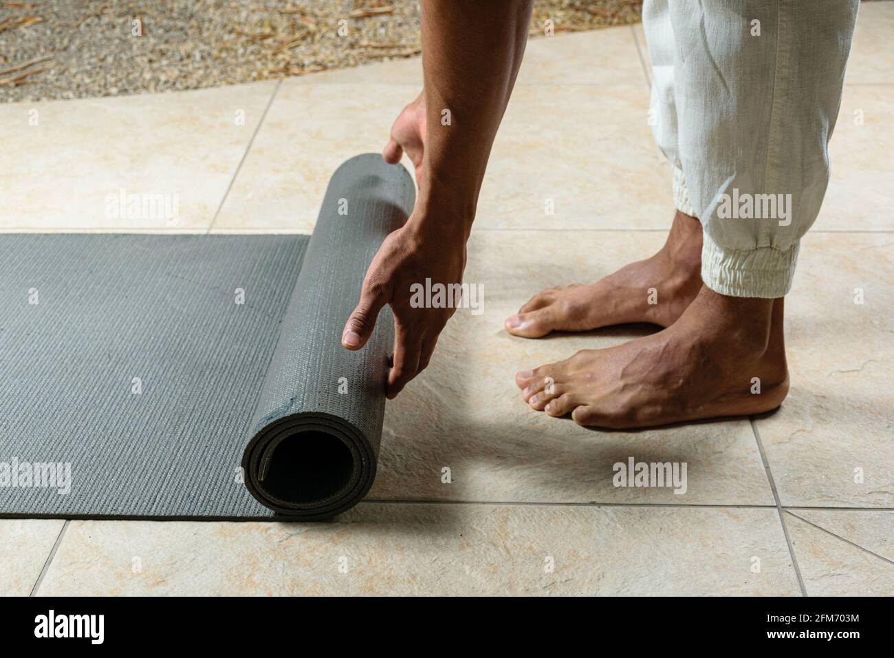 Primer plano de la practicante de yoga que se enrolla en su estera. Foto de stock