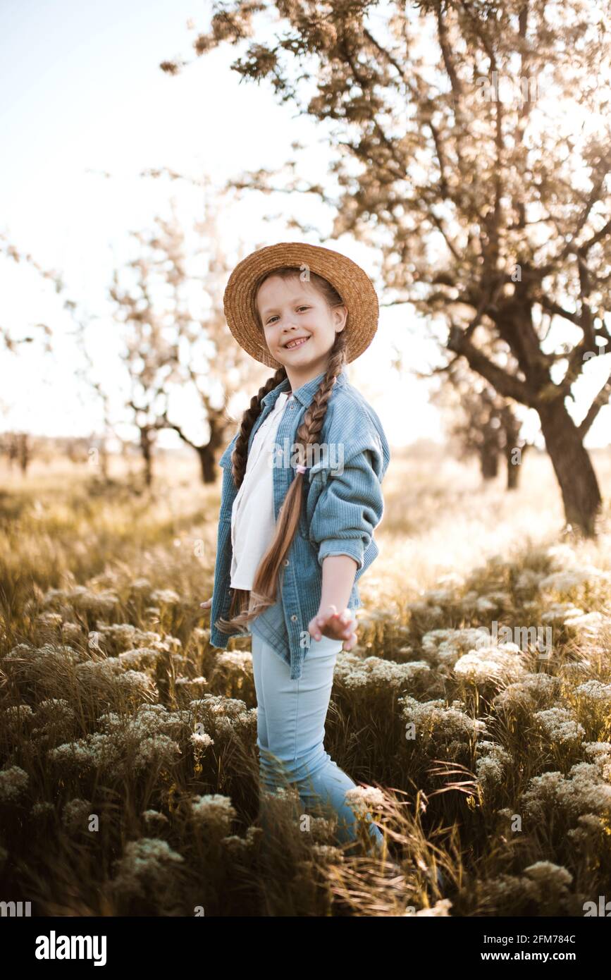 Niña de 4-5 años con estilo con sombrero de paja y ropa vaquera de moda en  la pradera al aire libre. Mirando la cámara. Infancia. Temporada de  primavera Fotografía de stock - Alamy