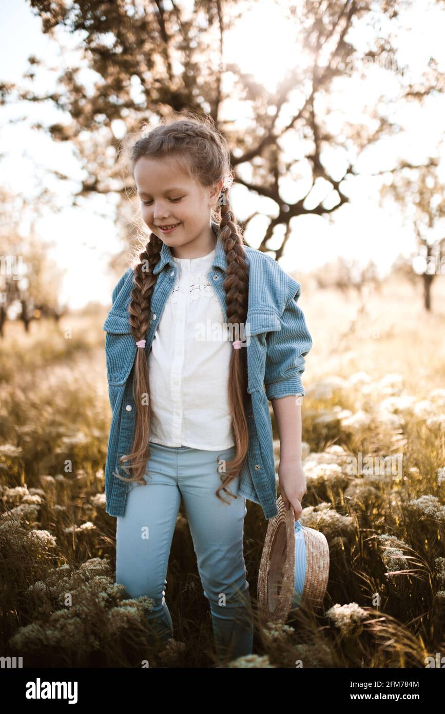 Linda niña de 4-5 años con ropa vaquera caminando en pradera con flores al  aire libre. Infancia. Temporada de primavera Fotografía de stock - Alamy