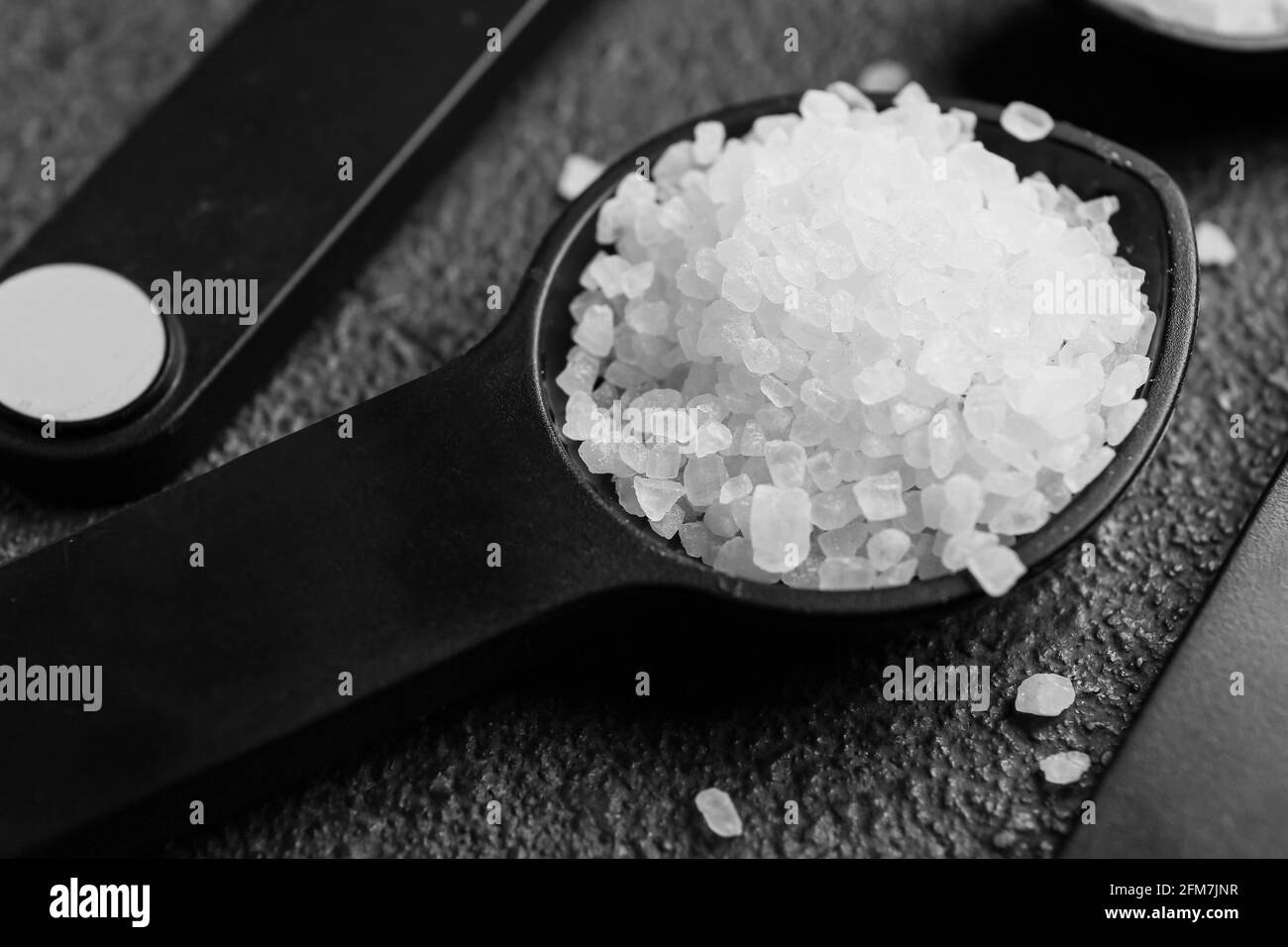 Cuchara de medir con sal sobre fondo oscuro Fotografía de stock - Alamy