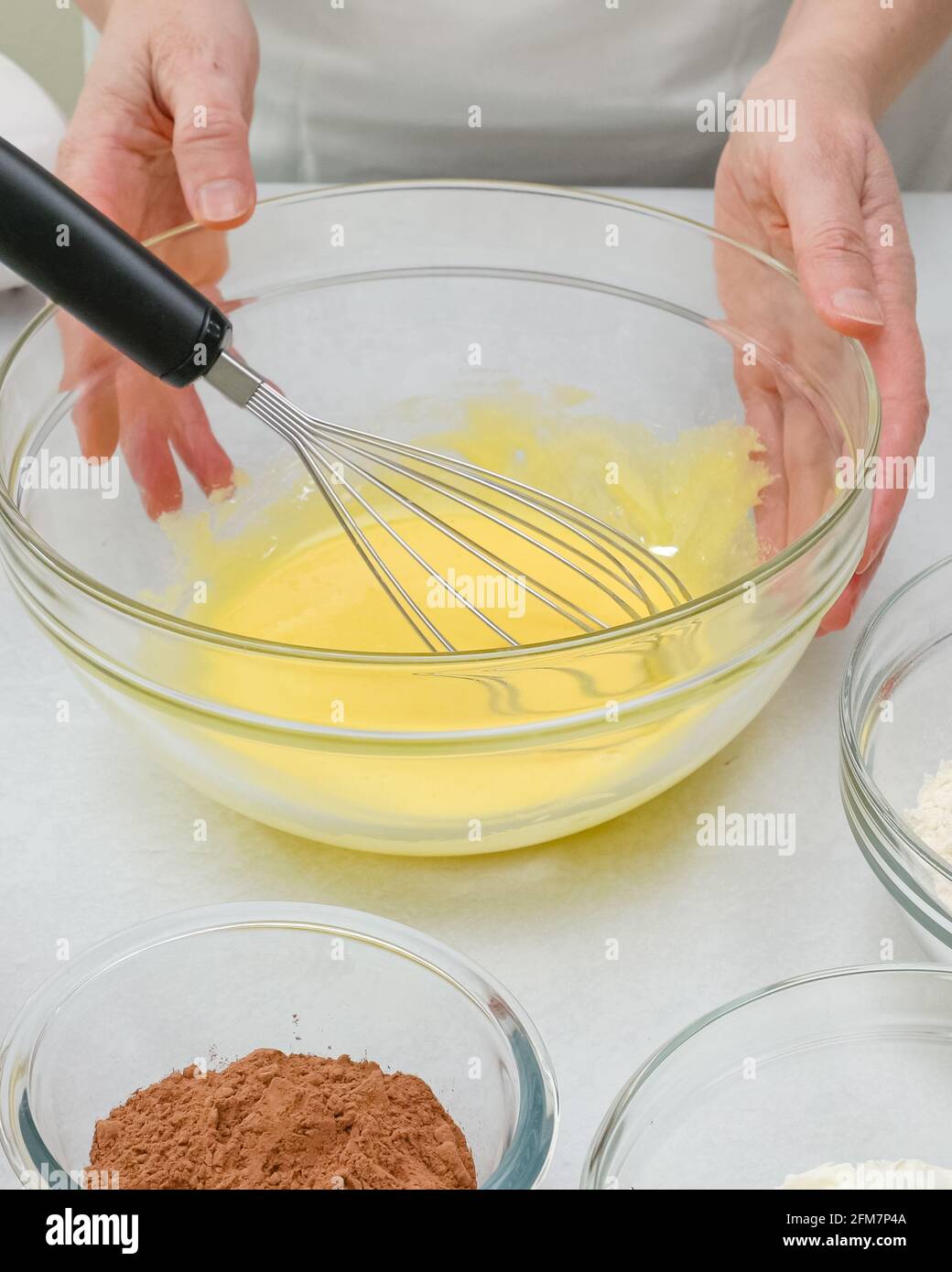 Bata las yemas de huevo con azúcar en un recipiente de cristal. Receta paso  a paso de pastel de chocolate, primer plano proceso de preparación, manos  de la mujer Fotografía de stock -